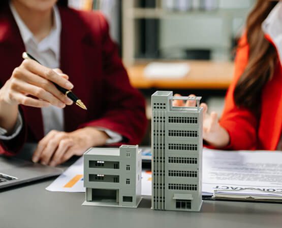Two people in professional attire analyzing a small, detailed architectural model of a building, symbolizing strategic planning, precise execution, and the tangible solution delivered for the engineering firm.
