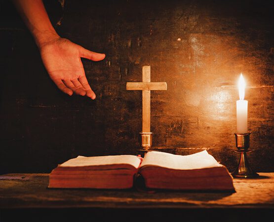 Hands clasped in prayer over a Bible and a wooden cross, illuminated by candlelight, symbolizing the deep trust and faith required for this spiritual service and the challenge of establishing digital authority.